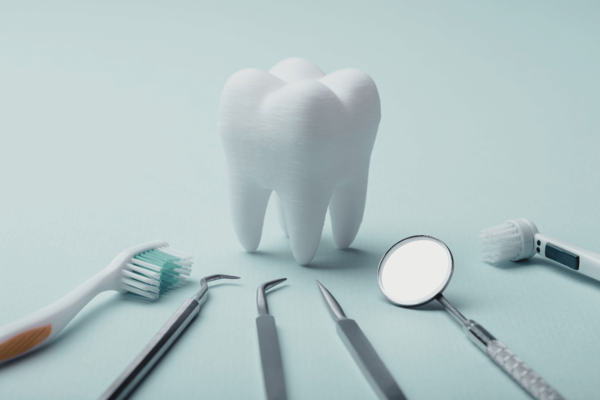 3D model of a tooth surrounded by dental tools, symbolizing dental care and hygiene.