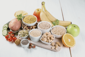 Assorted healthy foods including fruits, grains, and nuts on a wooden board, promoting oral health