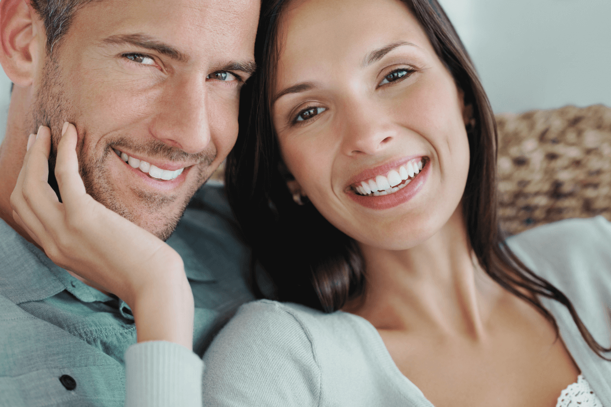 Happy couple smiling, showcasing the positive effects of a healthy smile on social interactions