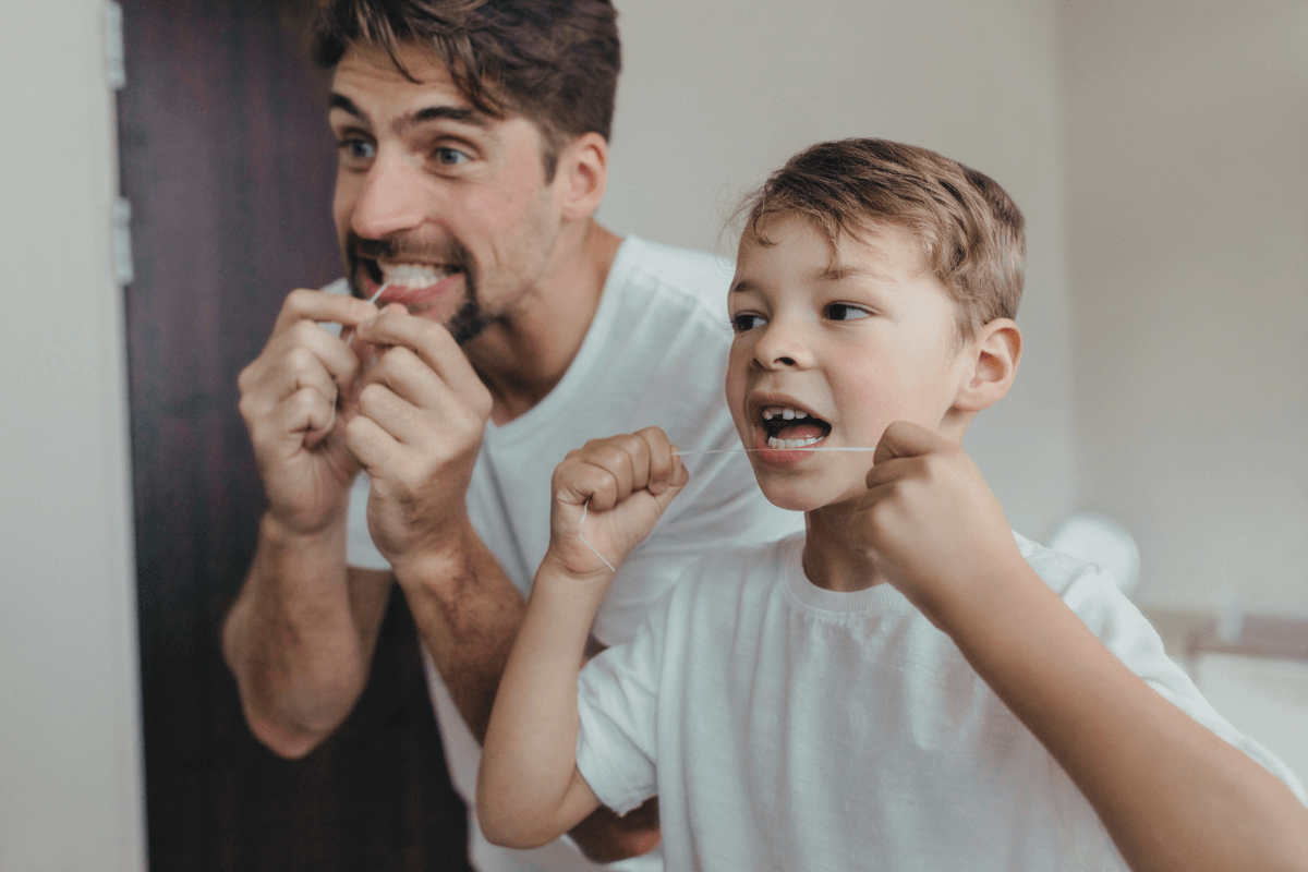 Father and son flossing together, emphasizing the importance of early dental habits